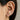 Close-up of an ear wearing gold earrings with a neutral background
